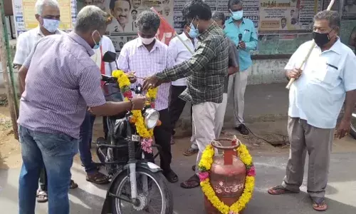 கரூரில்  எரிபொருள் விலை உயர்வு :  சிலிண்டர், வாகனத்துக்கு மாலை அணிவித்து கண்டனம்